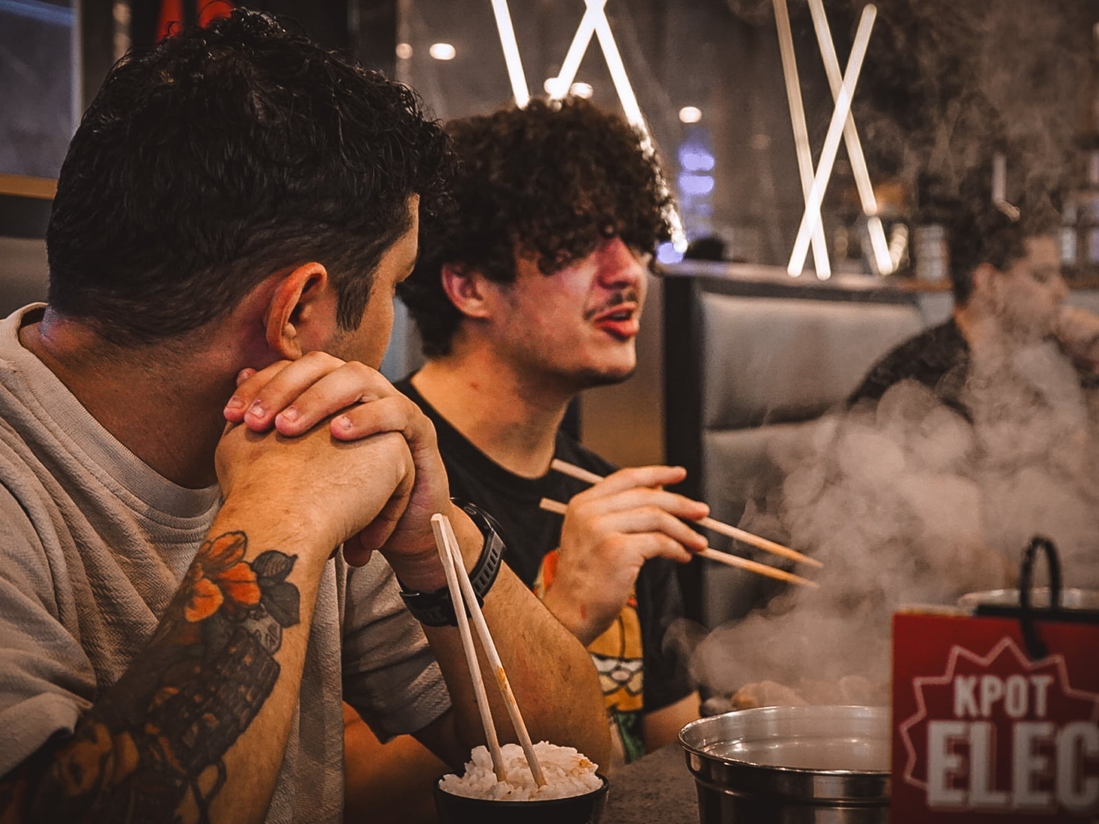Friends sharing a meal at KPOT Korean BBQ, steam rising from the grill